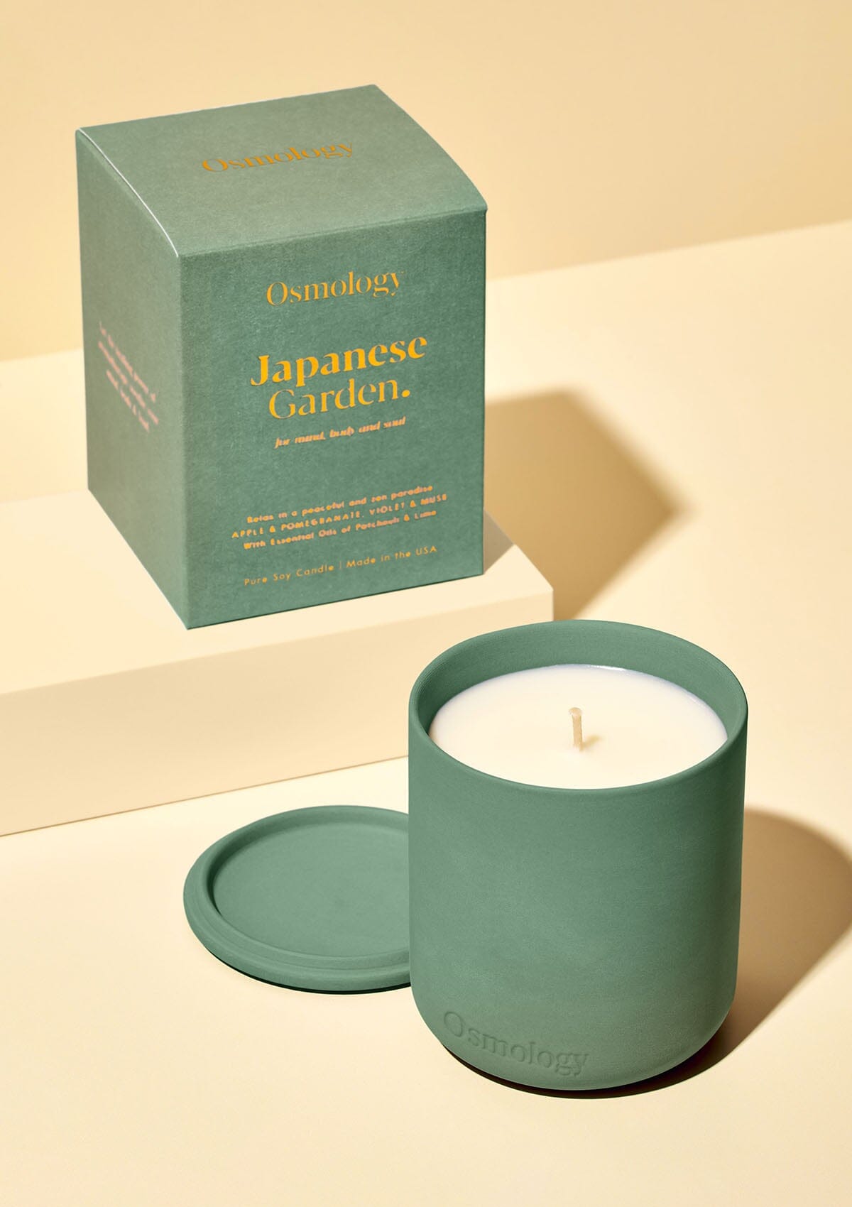 Green Japanese Garden candle by Osmology displayed next to product packaging on cream background