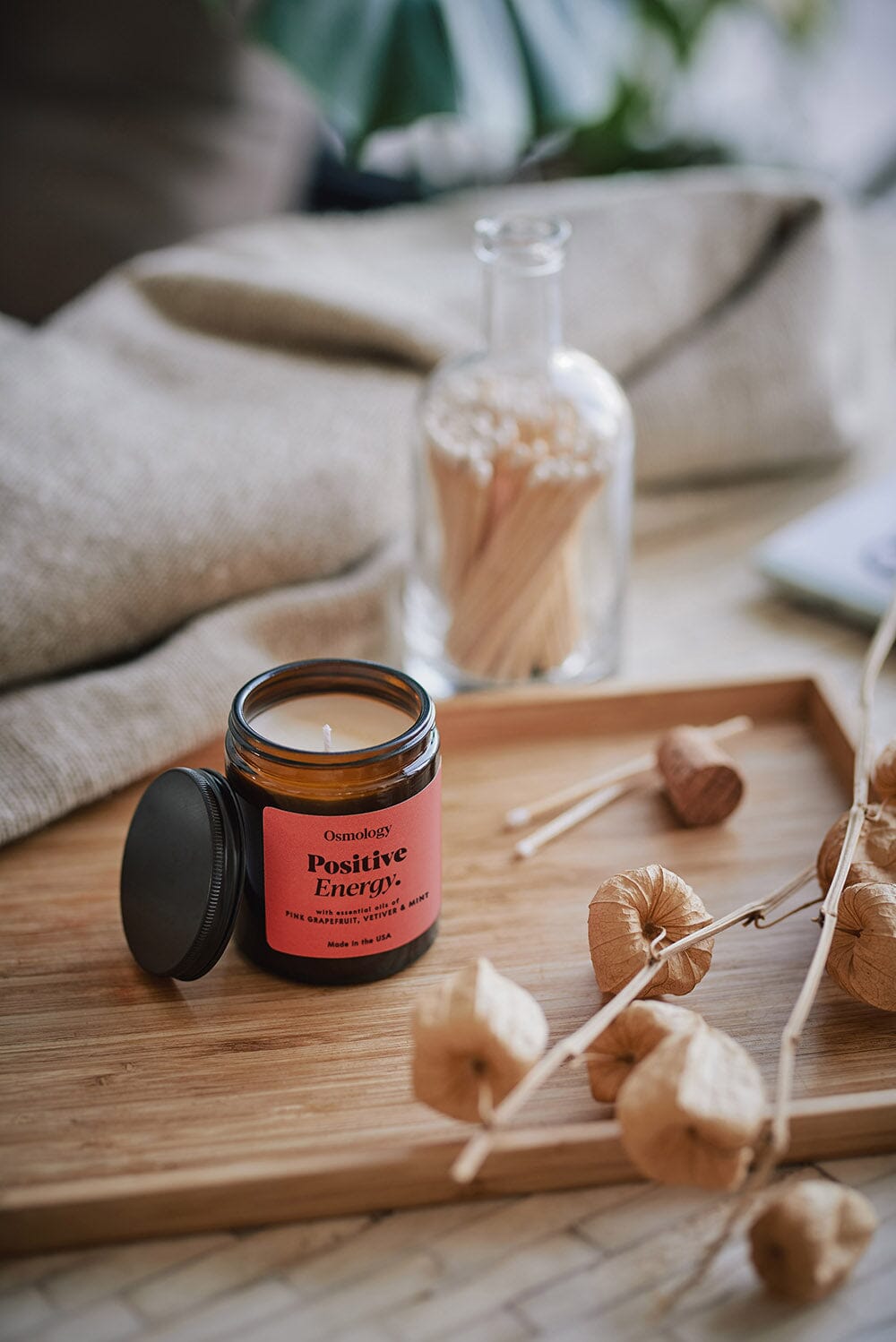 Osmology Jar candle with open lid on wooden tray