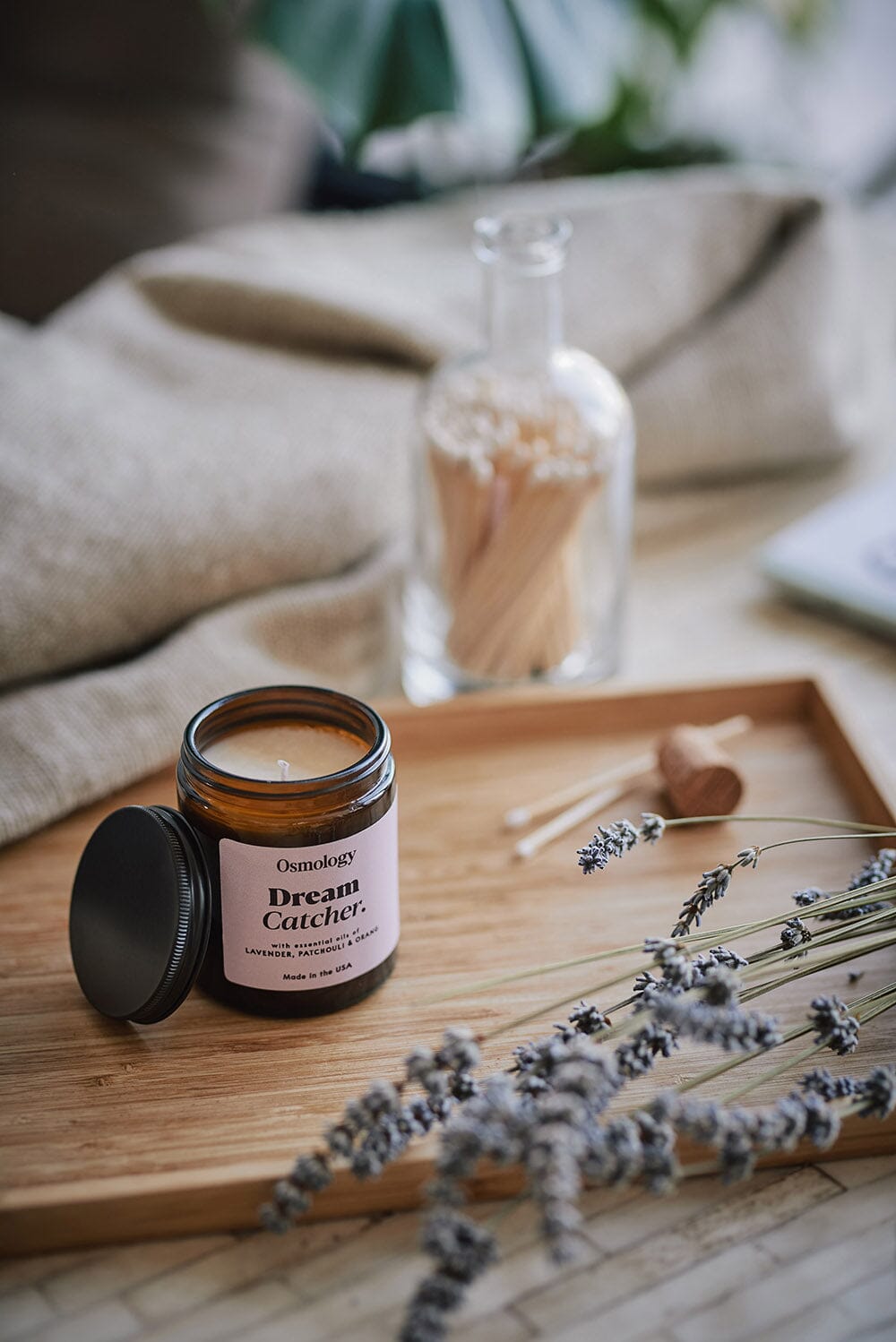 Osmology Dream Catcher jar candle on wooden tray, with lavender in foreground