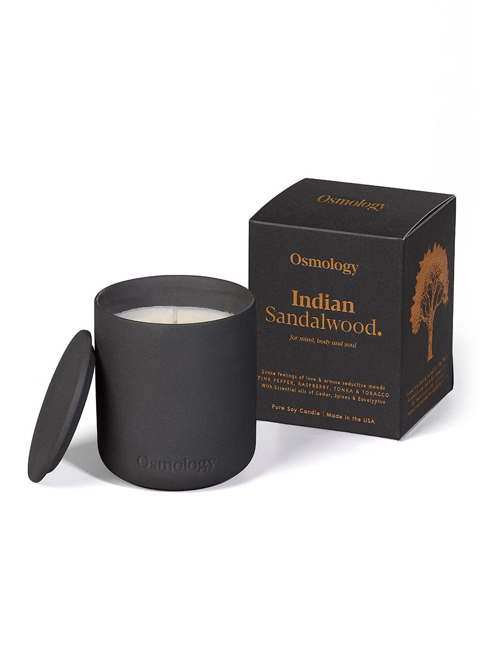 Osmology black ceramic indian sandalwood scented candle displayed next to decorative product packaging on white background