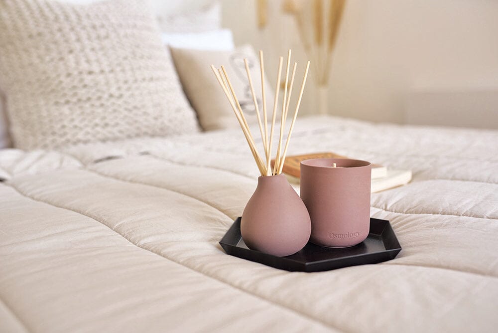 Moroccan Rose diffuser and Moroccan Rose candle on black tray, on bed