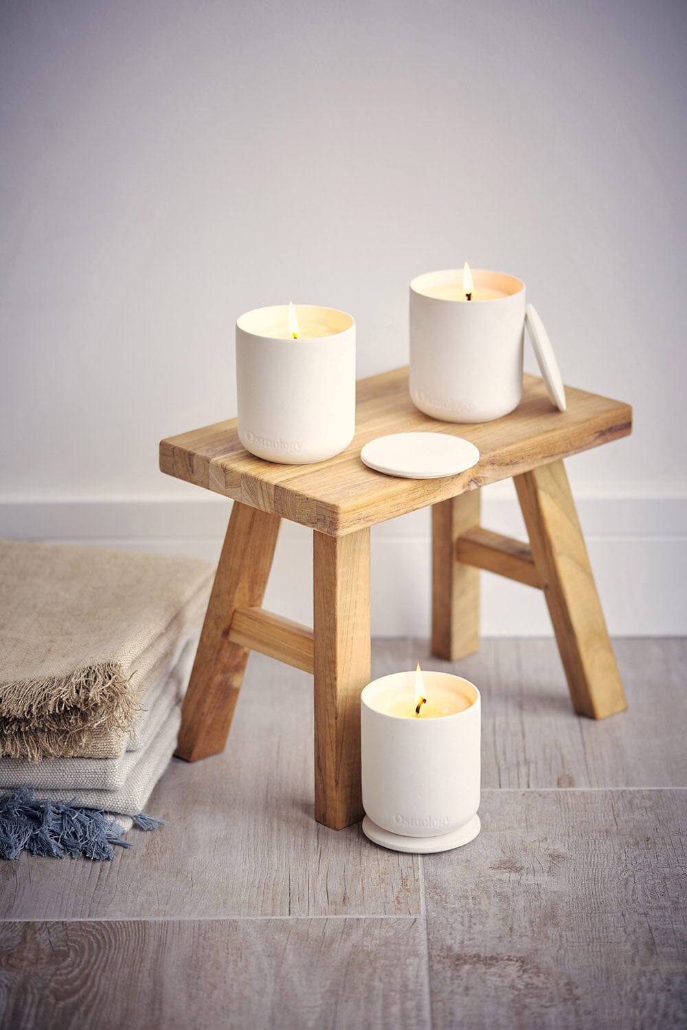 Three Osmology Nordic Cedar candles, arranged around stall, blankets on floor