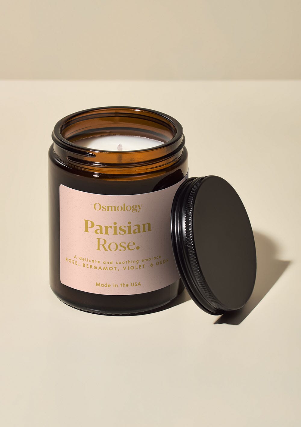 Osmology Parisian Rose jar candle with open lid on yellow-cream background