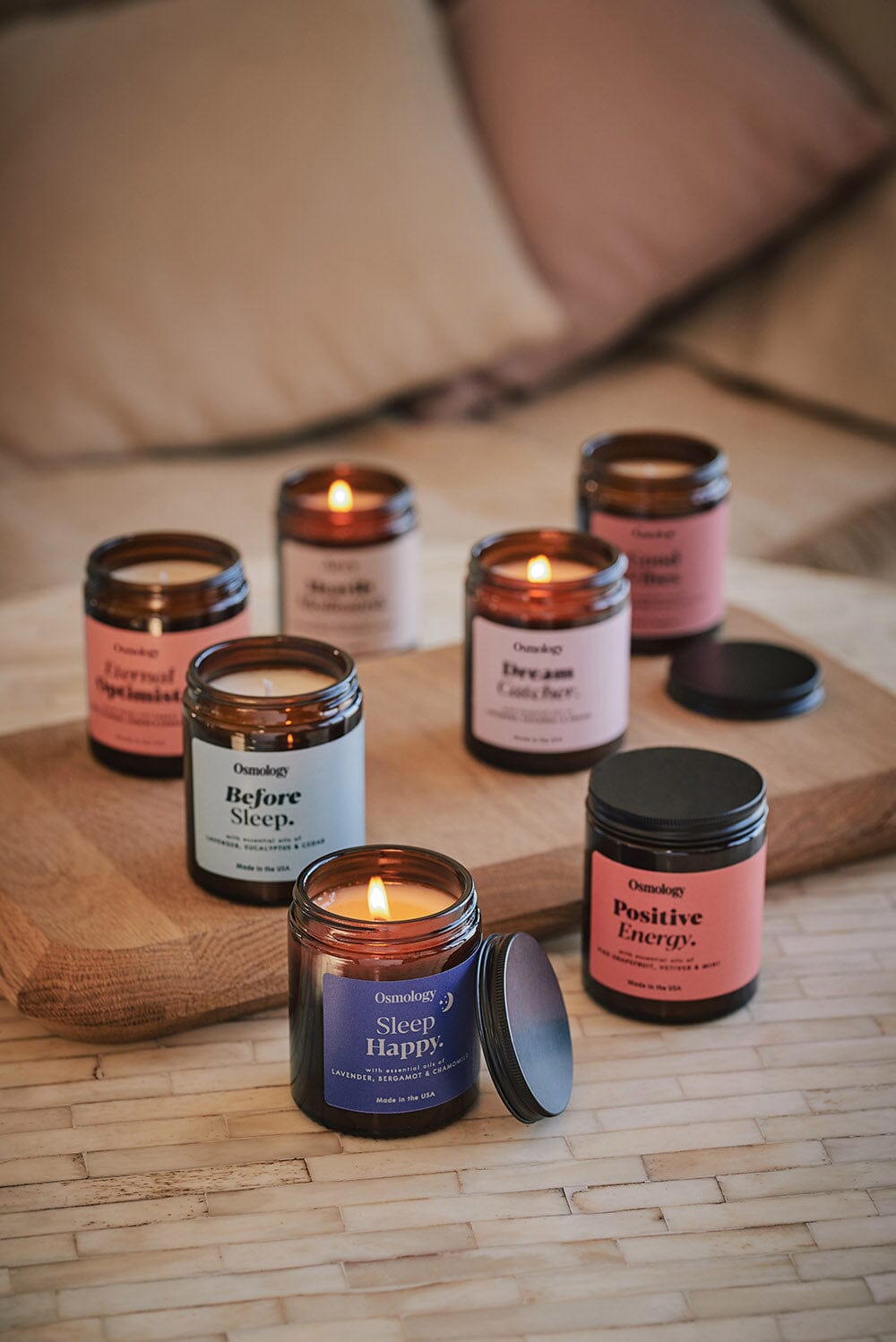 An array of jar candles arranged on wooden board and table, Sleep Happy candle at the front with lit flame